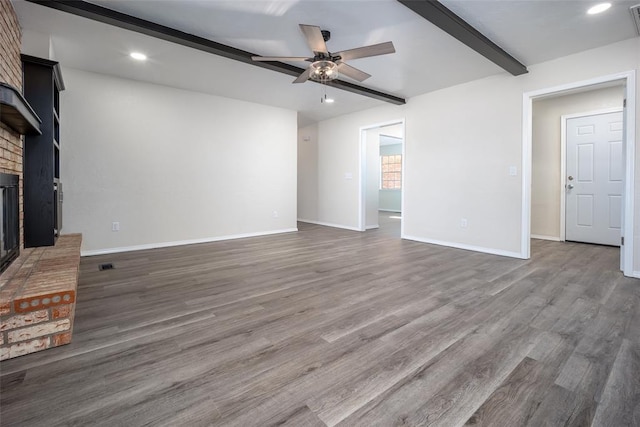 unfurnished living room with beam ceiling, ceiling fan, hardwood / wood-style floors, and a brick fireplace