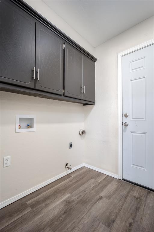 clothes washing area featuring hookup for an electric dryer, hookup for a washing machine, cabinets, gas dryer hookup, and dark wood-type flooring