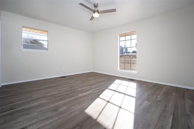 empty room with dark hardwood / wood-style flooring, plenty of natural light, and ceiling fan