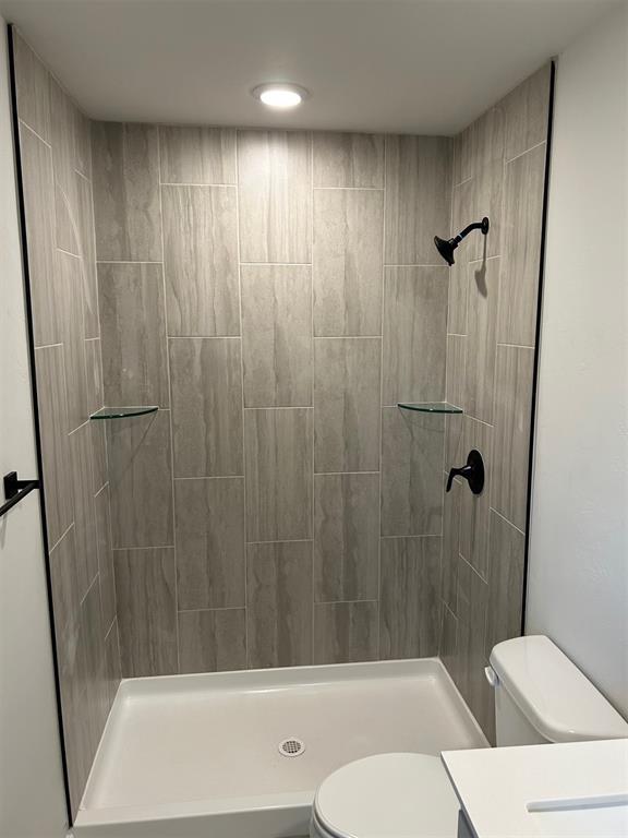 bathroom with vanity, toilet, and a tile shower