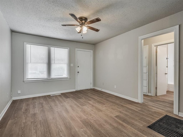 empty room featuring ceiling fan, light hardwood / wood-style floors, and a textured ceiling