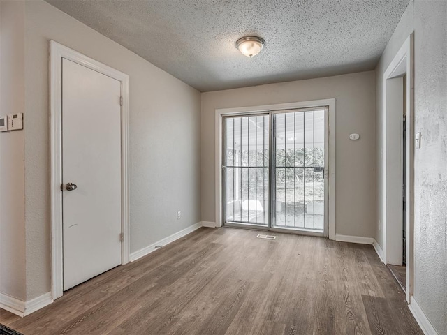 spare room featuring a textured ceiling and light wood-type flooring