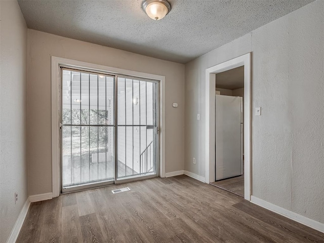 unfurnished room featuring a textured ceiling and light wood-type flooring