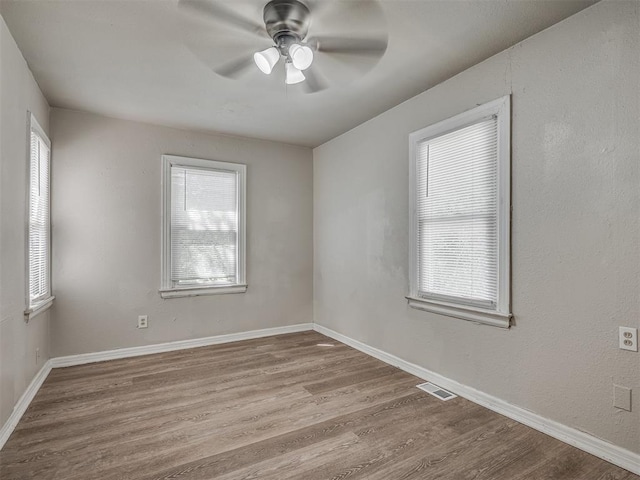 unfurnished room with a wealth of natural light, ceiling fan, and light hardwood / wood-style floors