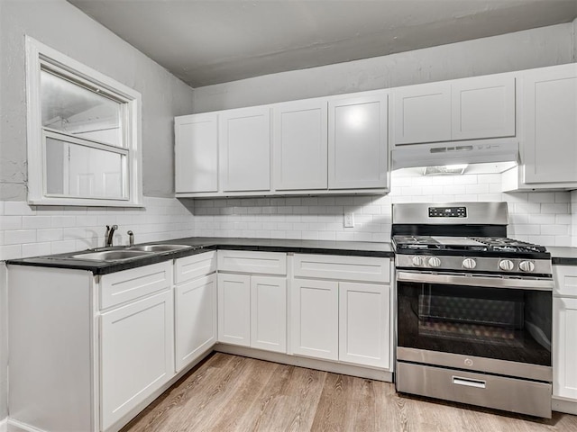 kitchen with light wood-type flooring, backsplash, gas stove, sink, and white cabinets