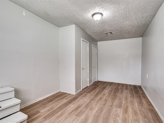 empty room with a textured ceiling and light wood-type flooring