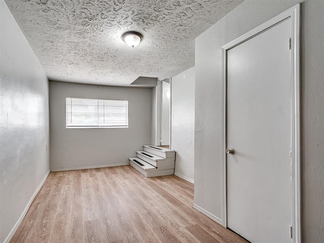 interior space featuring a textured ceiling, light hardwood / wood-style floors, and a closet