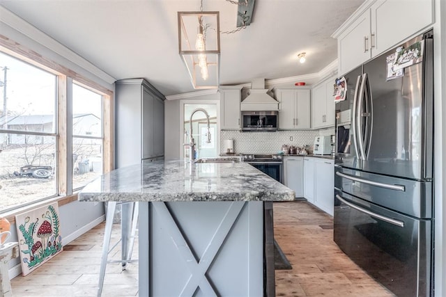 kitchen with stainless steel appliances, light hardwood / wood-style flooring, hanging light fixtures, and crown molding