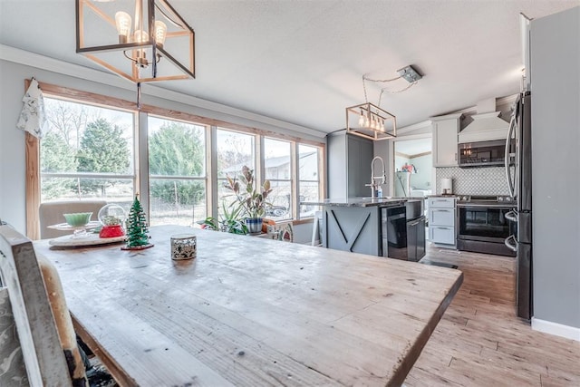 dining space with crown molding, sink, a chandelier, and light wood-type flooring