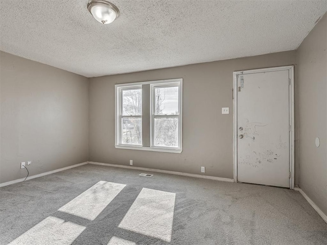 unfurnished room with light colored carpet and a textured ceiling