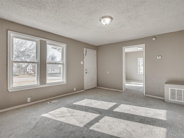 spare room featuring light carpet and a textured ceiling