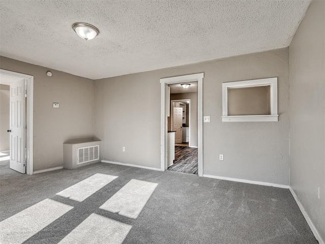 unfurnished bedroom with dark colored carpet and a textured ceiling