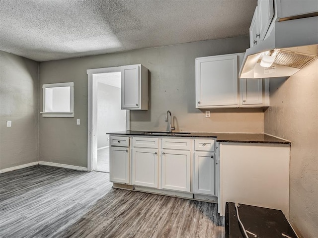 kitchen featuring white cabinetry, sink, a textured ceiling, and hardwood / wood-style flooring