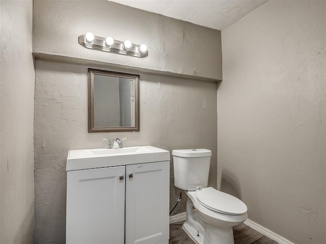 bathroom with hardwood / wood-style floors, vanity, and toilet