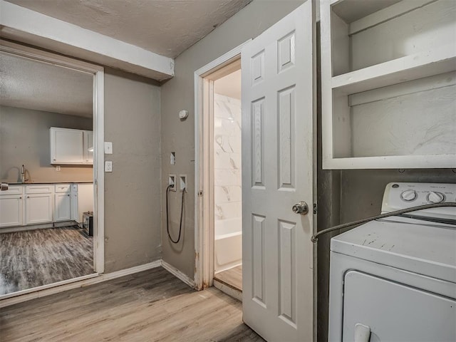 clothes washing area with a textured ceiling, washer / clothes dryer, and light hardwood / wood-style flooring