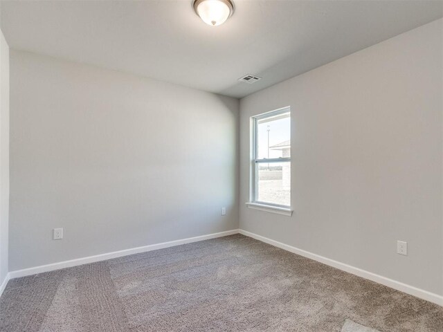 carpeted spare room with visible vents and baseboards