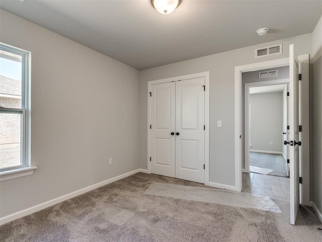 unfurnished bedroom with a closet, carpet flooring, visible vents, and baseboards