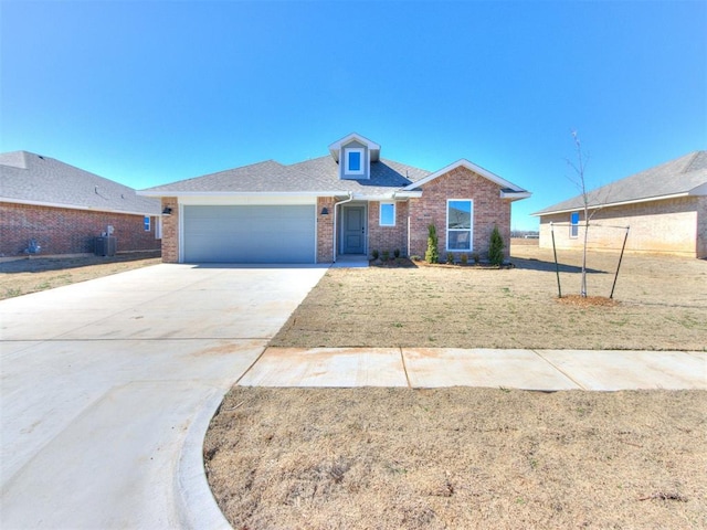 view of front of property with a garage, driveway, a front lawn, central AC, and brick siding