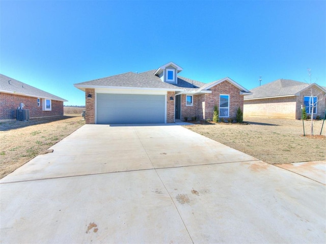 view of front of property with brick siding, central air condition unit, a front yard, a garage, and driveway