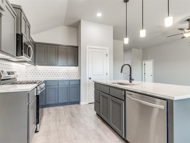 kitchen with light wood finished floors, a ceiling fan, stainless steel appliances, light countertops, and a sink