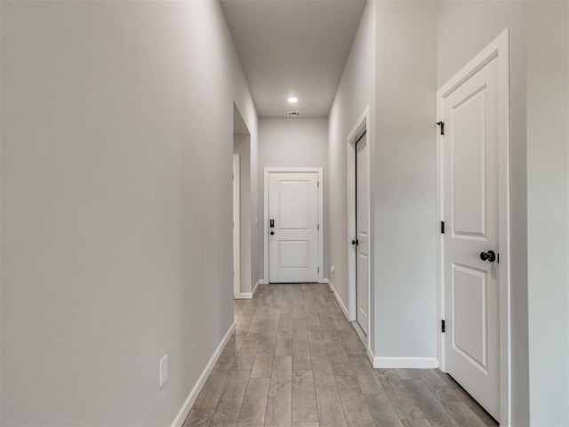 corridor featuring light wood-style flooring and baseboards