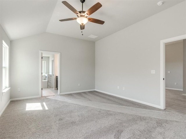 spare room featuring light carpet, ceiling fan, vaulted ceiling, and baseboards