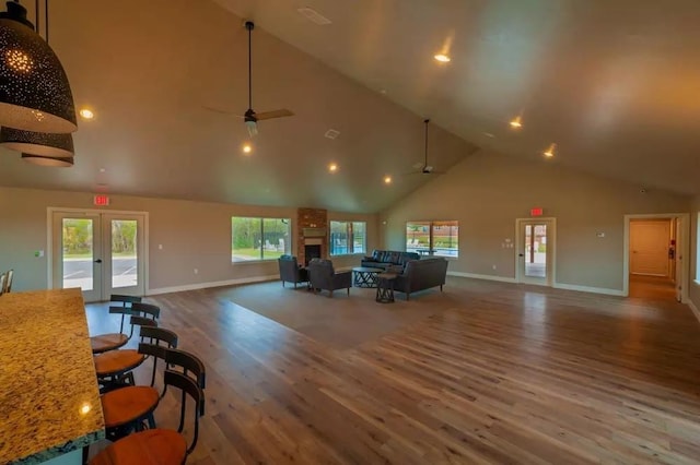 living room with ceiling fan, french doors, high vaulted ceiling, and hardwood / wood-style flooring