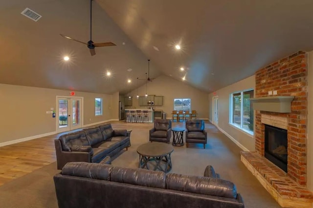 living room with ceiling fan, french doors, a brick fireplace, high vaulted ceiling, and wood-type flooring