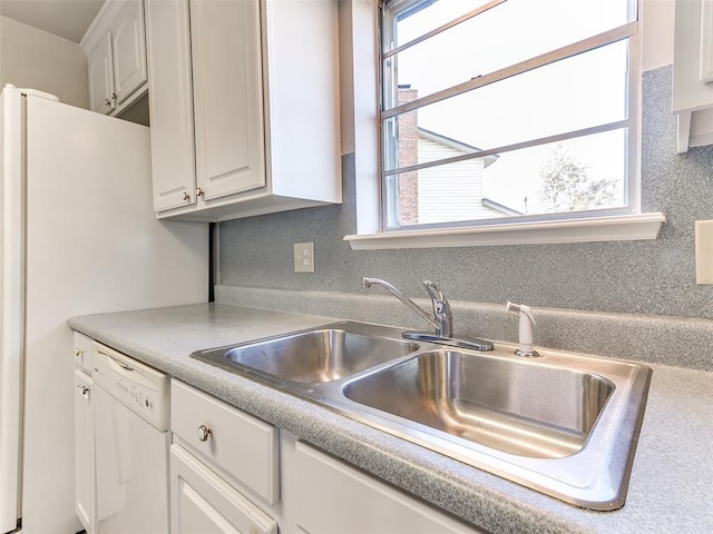 kitchen with dishwasher, white cabinetry, and sink