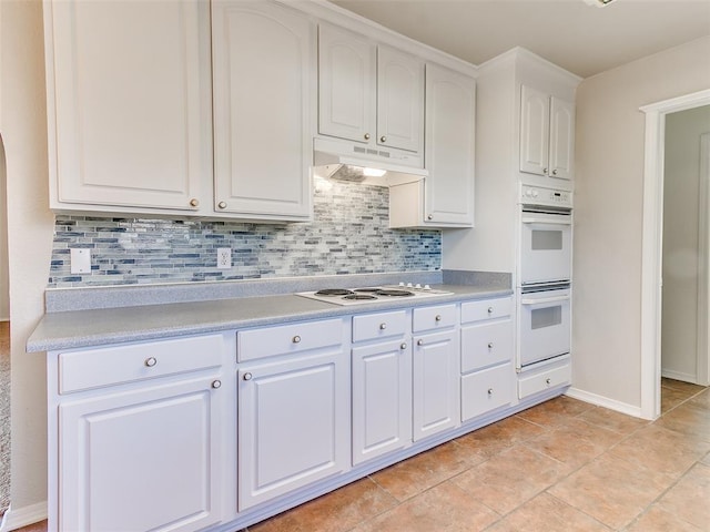 kitchen featuring white appliances, white cabinetry, backsplash, and light tile patterned floors