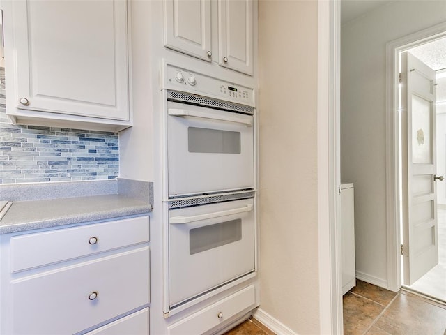 kitchen with decorative backsplash, white cabinetry, and double oven