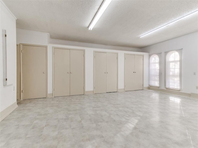 interior space with a textured ceiling, crown molding, and multiple closets