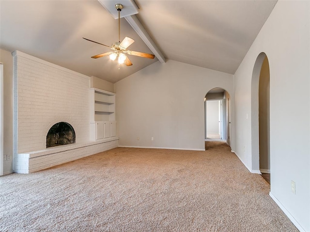 unfurnished living room with ceiling fan, built in features, lofted ceiling with beams, carpet floors, and a fireplace