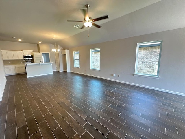 unfurnished living room featuring ceiling fan with notable chandelier, lofted ceiling, and dark wood-type flooring