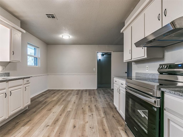 kitchen featuring white cabinetry, electric range, dark stone countertops, a textured ceiling, and light wood-type flooring