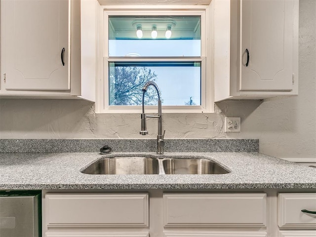 kitchen featuring white cabinetry, sink, and light stone counters