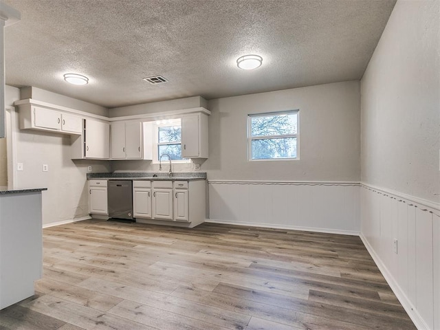 kitchen featuring white cabinets, a textured ceiling, and light hardwood / wood-style flooring