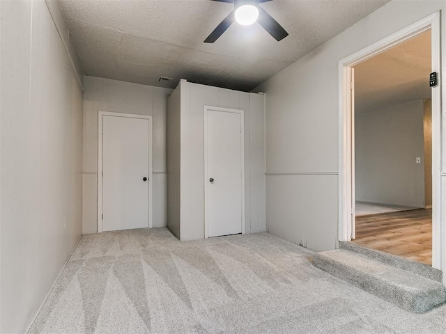 unfurnished bedroom with ceiling fan, light colored carpet, and a textured ceiling