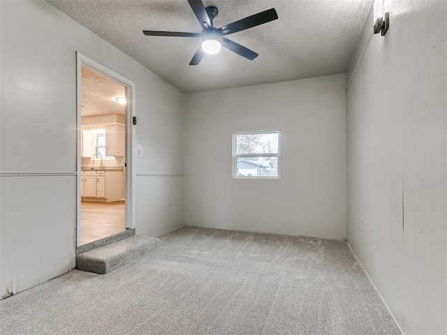 unfurnished room with carpet flooring, plenty of natural light, ceiling fan, and a textured ceiling