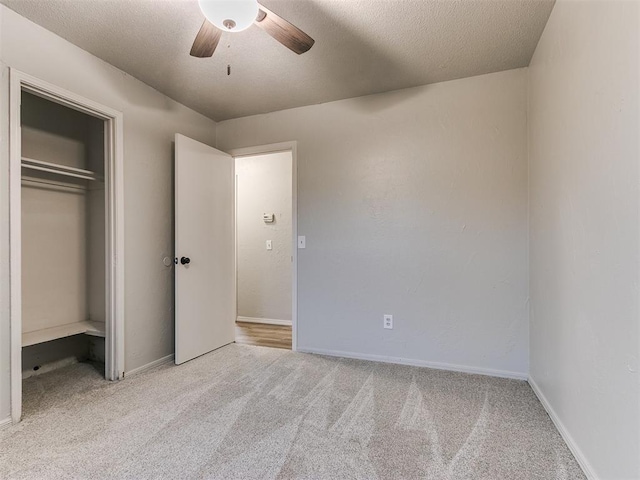 unfurnished bedroom with light carpet, a textured ceiling, a closet, and ceiling fan