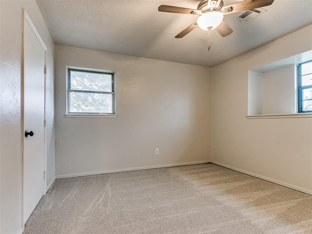 carpeted spare room featuring a textured ceiling, plenty of natural light, and ceiling fan