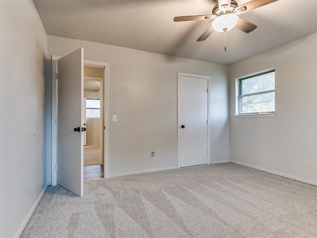 unfurnished bedroom featuring ceiling fan, light carpet, and a textured ceiling