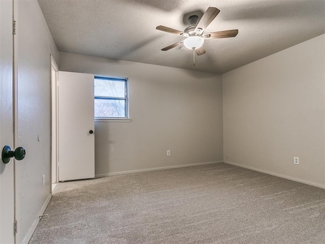 empty room with ceiling fan, light colored carpet, and a textured ceiling