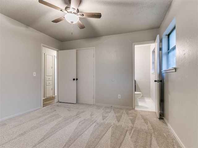 unfurnished bedroom with light carpet, a textured ceiling, connected bathroom, and ceiling fan