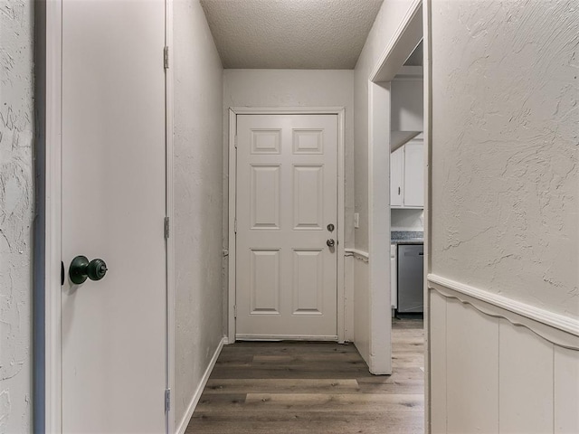 doorway with a textured ceiling and dark wood-type flooring