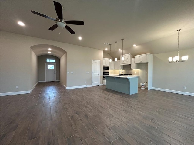 kitchen with white cabinetry, hanging light fixtures, dark hardwood / wood-style flooring, a center island with sink, and ceiling fan with notable chandelier