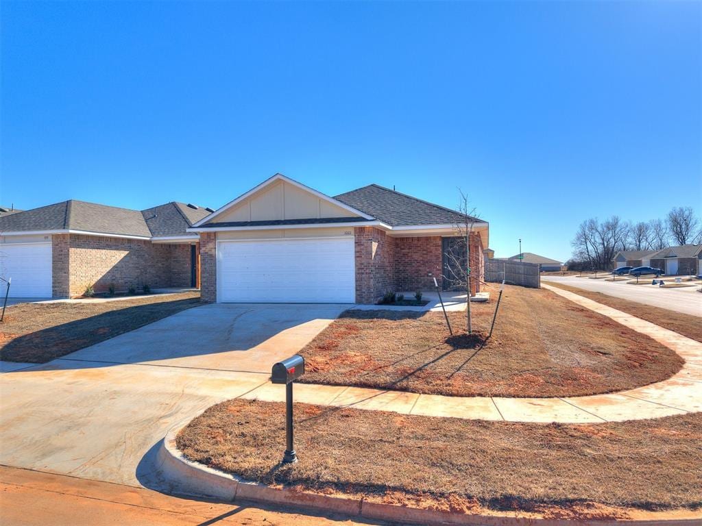 single story home featuring a shingled roof, concrete driveway, an attached garage, board and batten siding, and brick siding