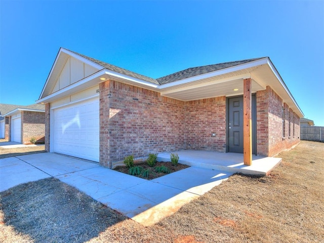 view of front of property featuring brick siding, roof with shingles, an attached garage, board and batten siding, and driveway