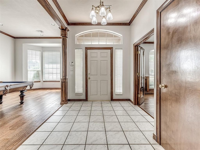 entrance foyer with ornamental molding, light hardwood / wood-style floors, and a notable chandelier