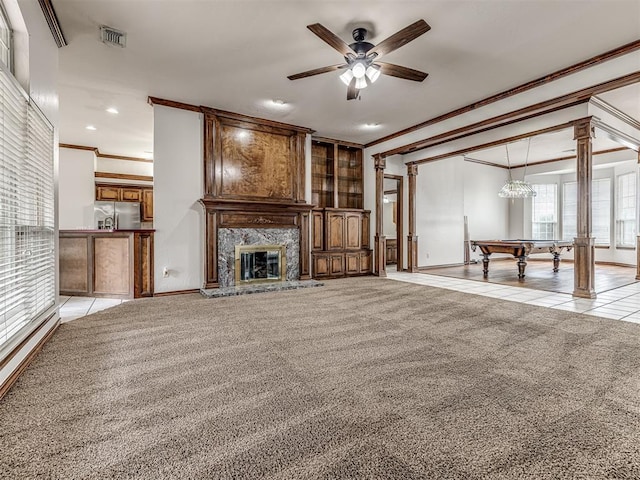 unfurnished living room featuring light carpet, billiards, ceiling fan, ornamental molding, and decorative columns